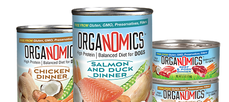 Four cans of Organomics dog food featuring different flavors: Chicken Dinner, Salmon and Duck Dinner, and Beef & Pork Dinner, labeled as high protein and free from gluten, GMO, preservatives, and fillers.